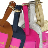 Close-up of adjustable buckle straps on Duo Threads needlepoint luggage tags in gold, silver, hot pink, navy, and brown.