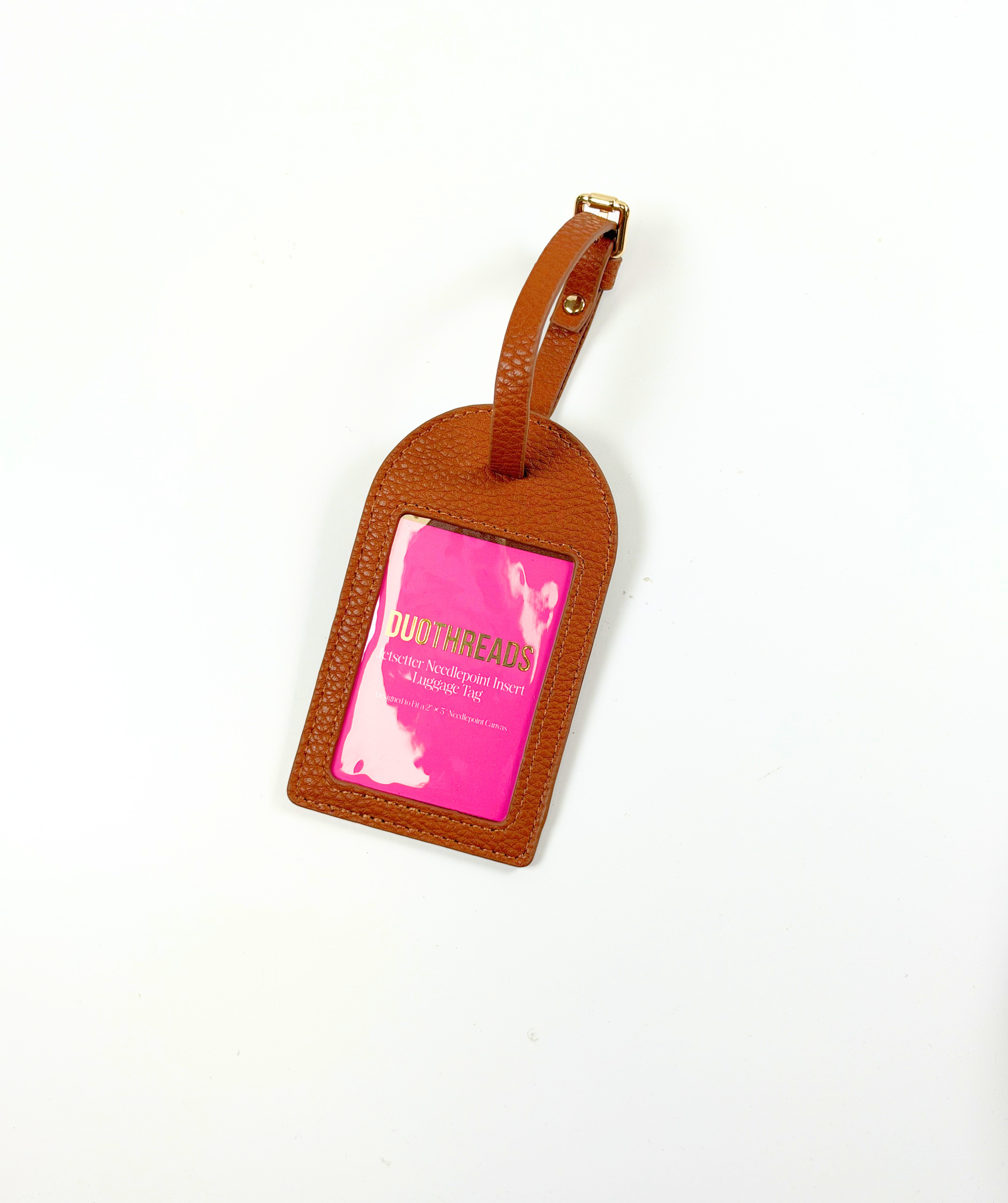 Brown self-finishing needlepoint luggage tag with textured exterior, adjustable strap, and clear rectangular window for personalized stitching.