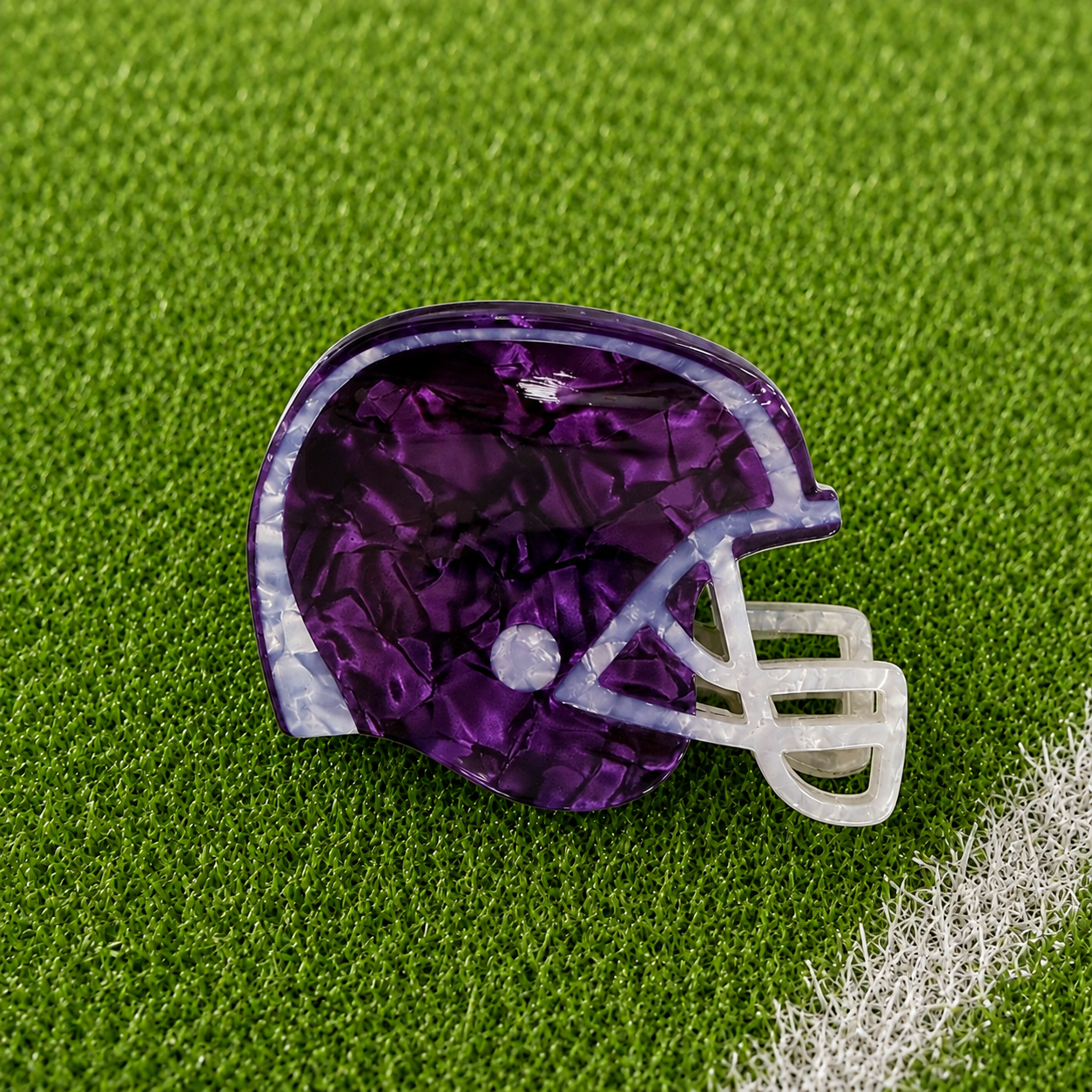 A purple football helmet shaped claw clip on green turf background