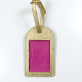 Metallic gold self-finishing needlepoint luggage tag featuring a textured finish, adjustable strap, and rectangular needlepoint window.