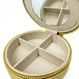 Open gold needlepoint travel jewelry case featuring a built-in mirror, divided jewelry compartments, and soft cream interior lining.