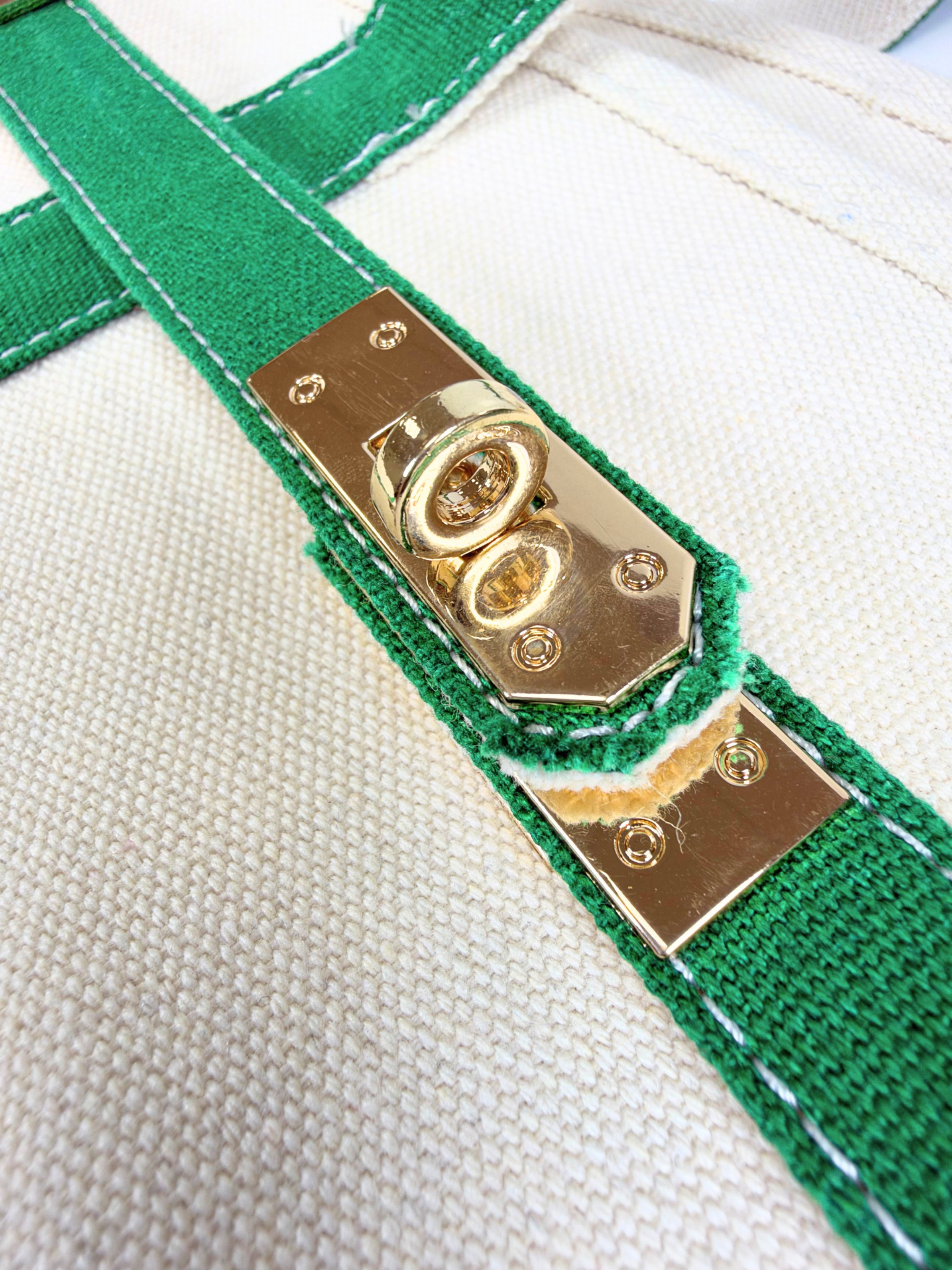 Detailed view of gold-tone turn-lock hardware and green trim on the Parker self-finishing needlepoint canvas boat tote.