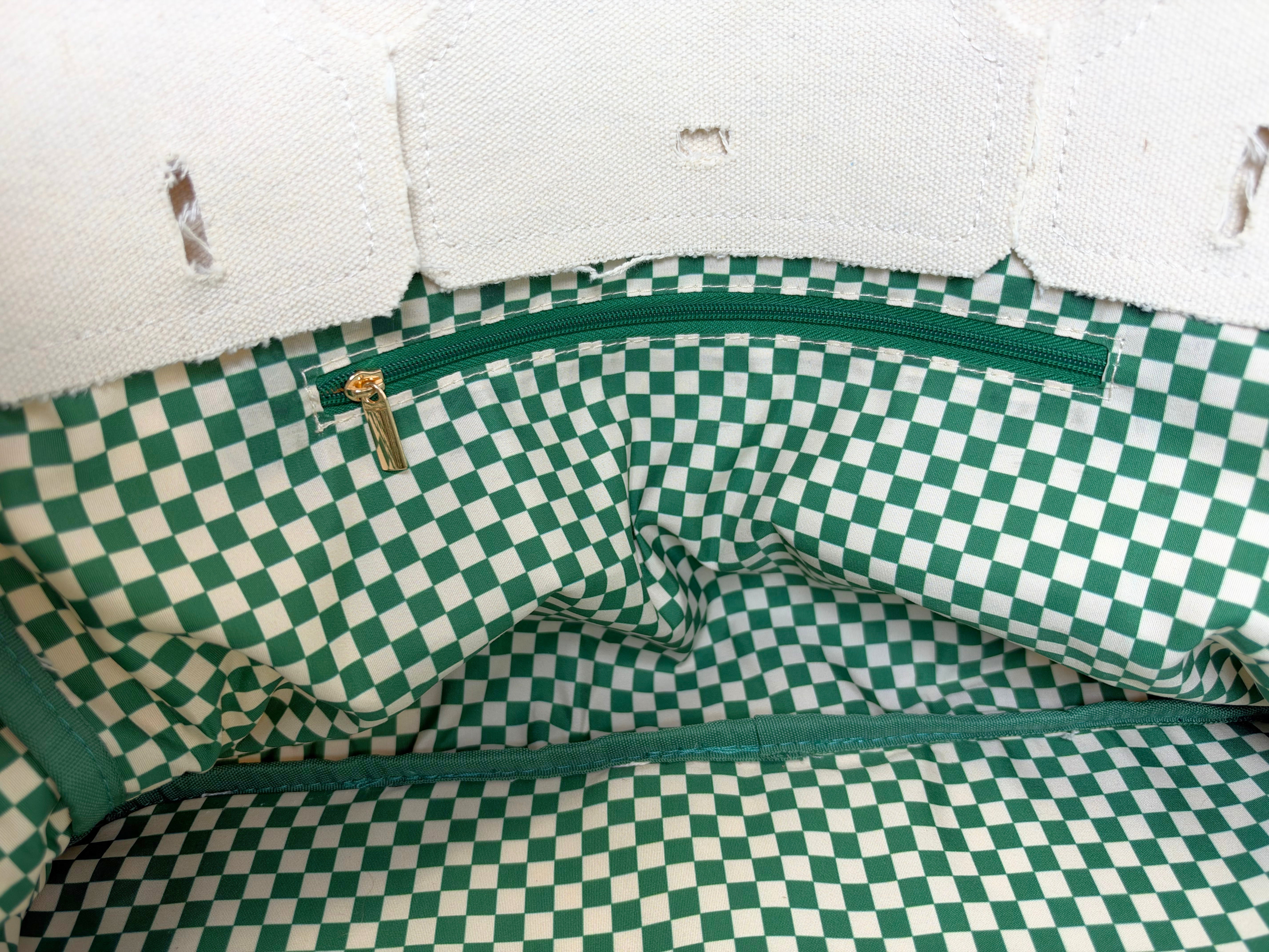 Interior view of the Parker needlepoint canvas tote featuring green and white gingham lining and a coordinating interior zippered pocket.