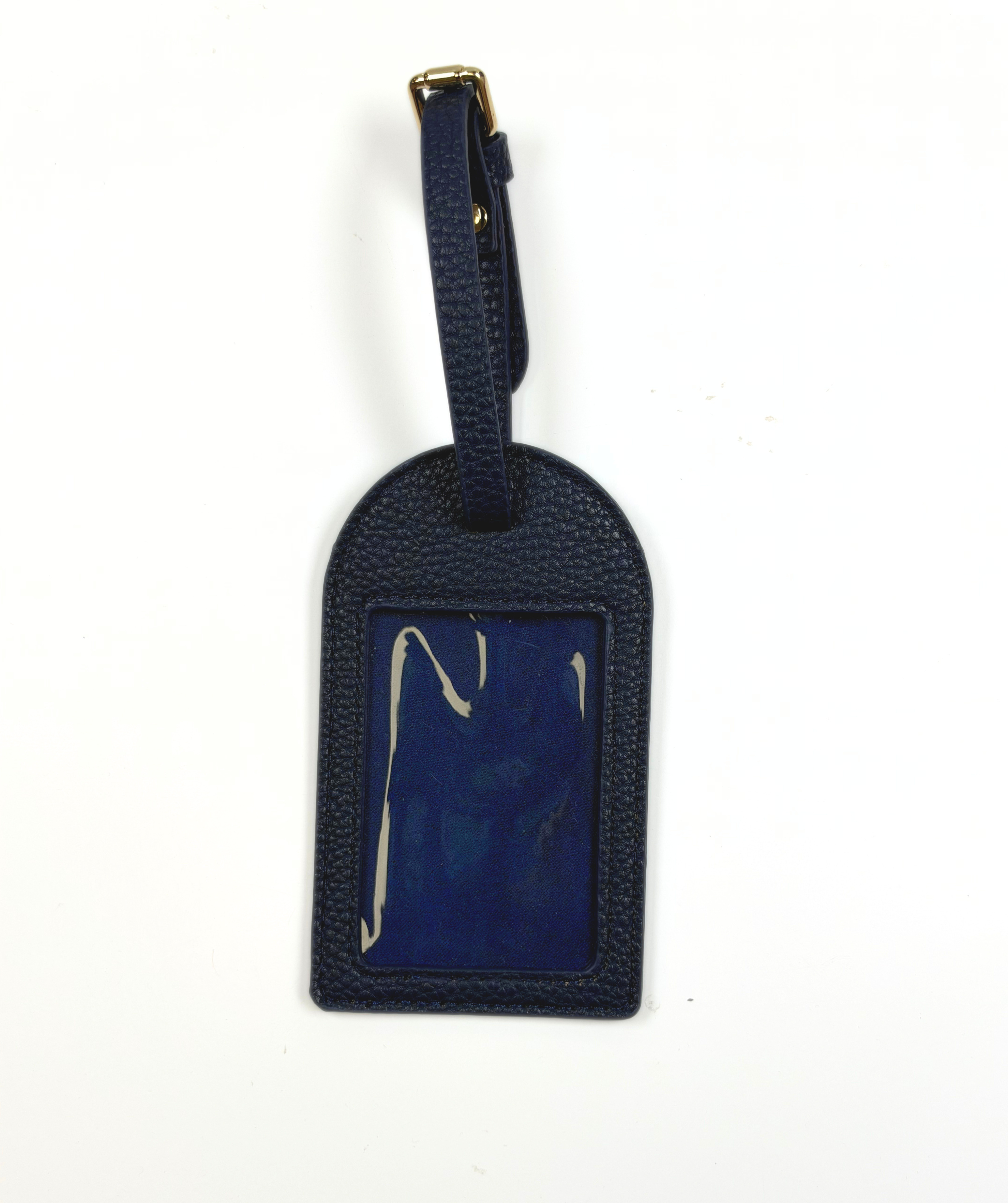 Navy blue self-finishing needlepoint luggage tag featuring a textured exterior, adjustable buckle strap, and rectangular needlepoint insert.
