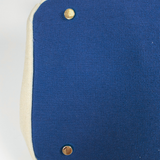Close-up of navy blue bottom panel with protective gold metal feet on the Parker canvas needlepoint boat tote.