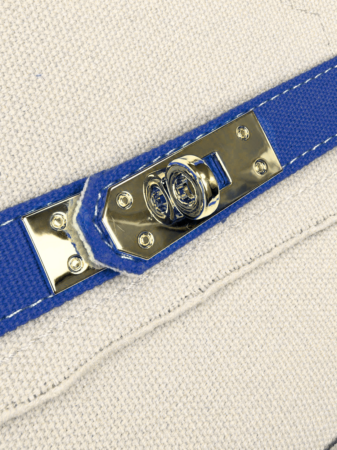Close-up of the Parker needlepoint boat tote's polished gold-tone hardware, navy blue trim, and textured cream canvas.
