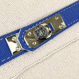 Close-up of the Parker needlepoint boat tote's polished gold-tone hardware, navy blue trim, and textured cream canvas.