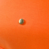 Close-up of the Parker canvas tote's orange bottom panel featuring a protective gold metal foot.