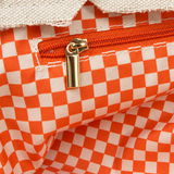 Close-up of the Parker needlepoint tote's interior zippered pocket with gold-tone zipper and orange and white gingham lining.