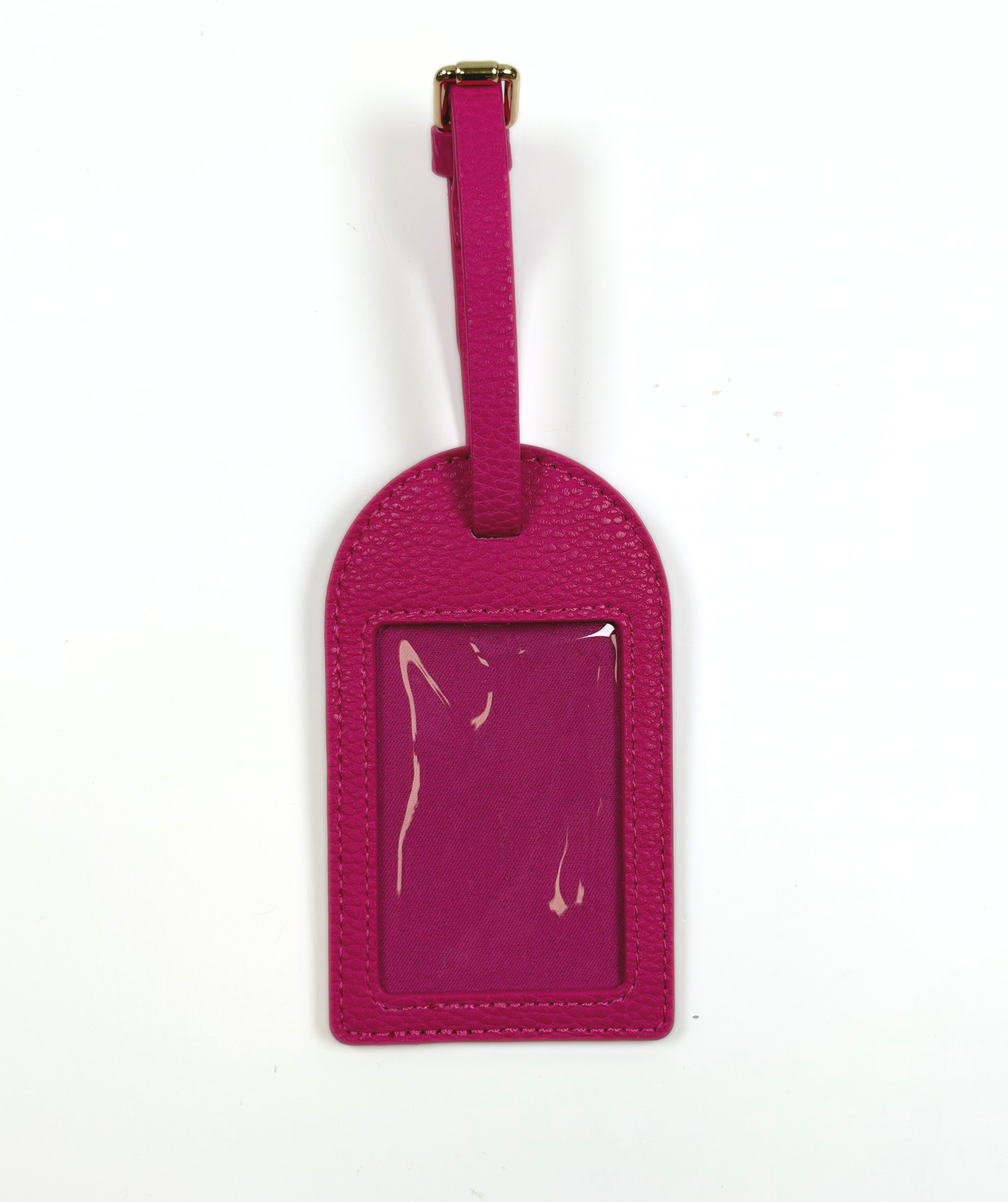 Hot pink self-finishing needlepoint luggage tag with textured exterior, adjustable strap, and clear window for needlepoint personalization.