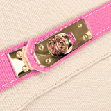Close-up of polished gold-tone turn-lock hardware on the Parker needlepoint tote with bright pink trim and cream canvas exterior.