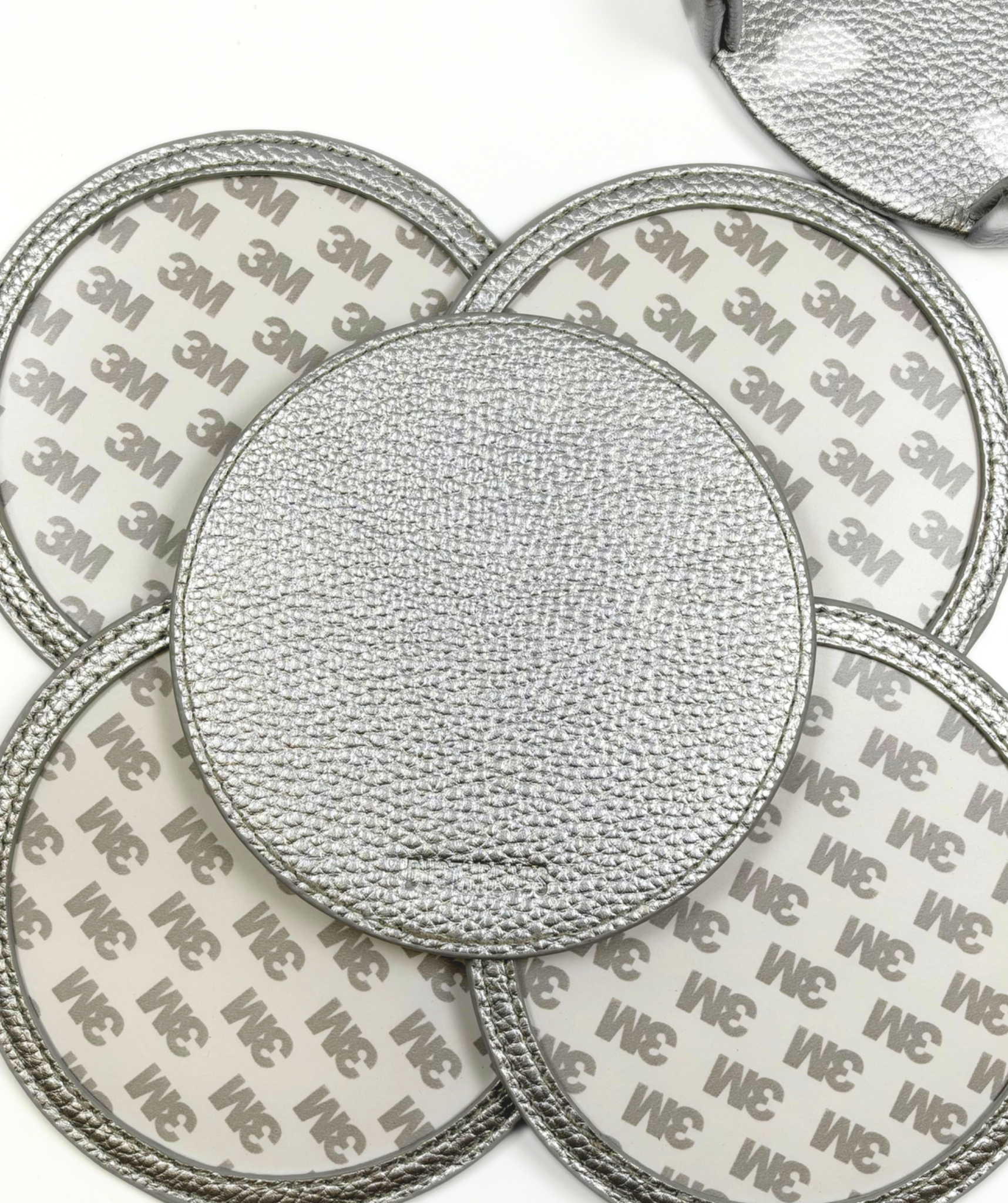 Metallic silver self-finishing needlepoint coaster set featuring four round coasters with textured silver trim and customizable needlepoint inserts.