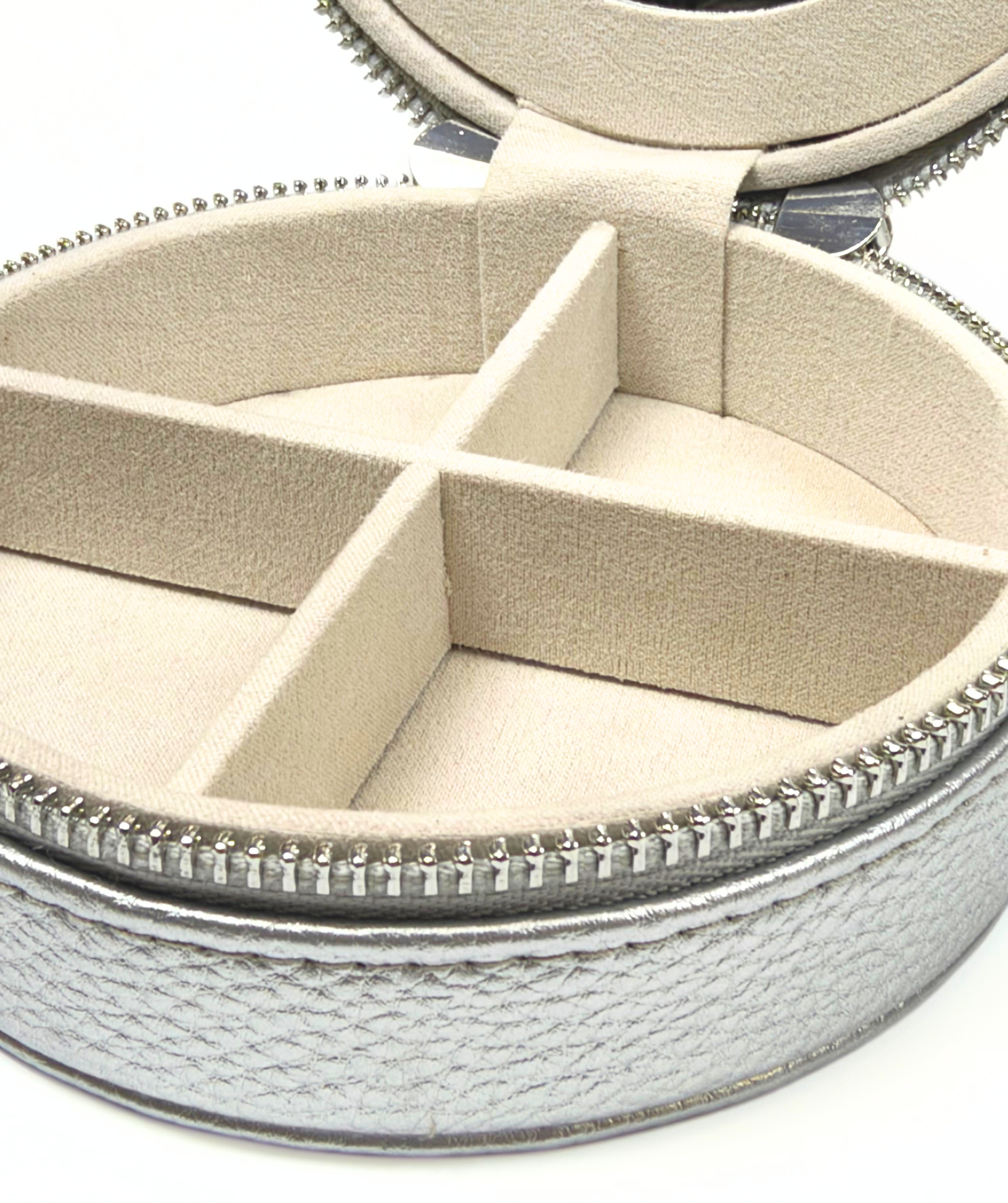 Close-up of silver self-finishing needlepoint travel jewelry case showing soft-lined jewelry compartments and zippered exterior.