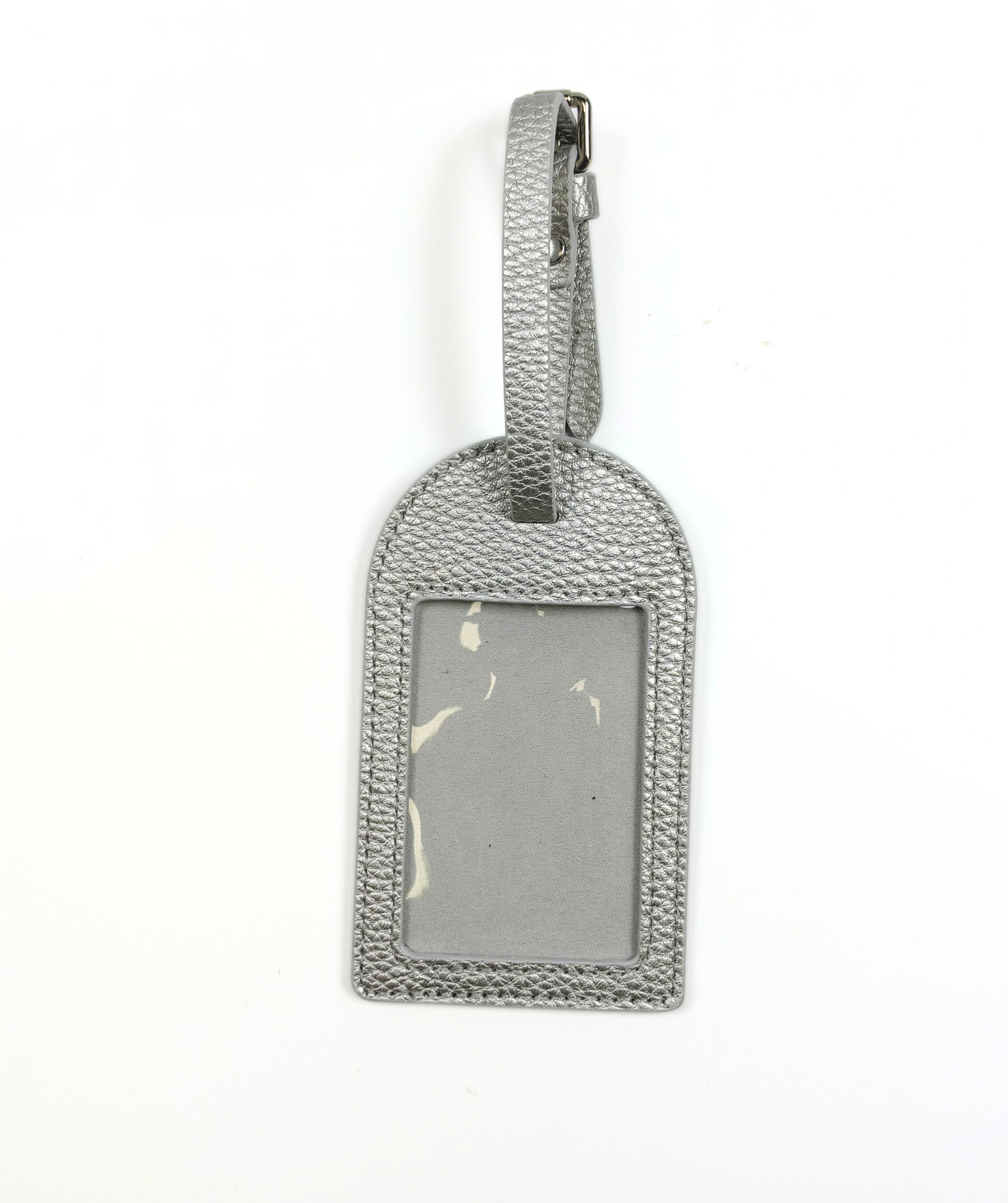 Metallic silver self-finishing needlepoint luggage tag with adjustable strap and rectangular window for a personalized needlepoint canvas.