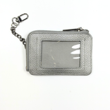 Silver metallic self-finishing needlepoint wallet featuring a rectangular needlepoint insert window, zippered closure, and silver clip-on chain.