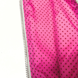 Close-up of the needlepoint travel case's bright pink interior lining with a playful black polka dot pattern and zippered opening.