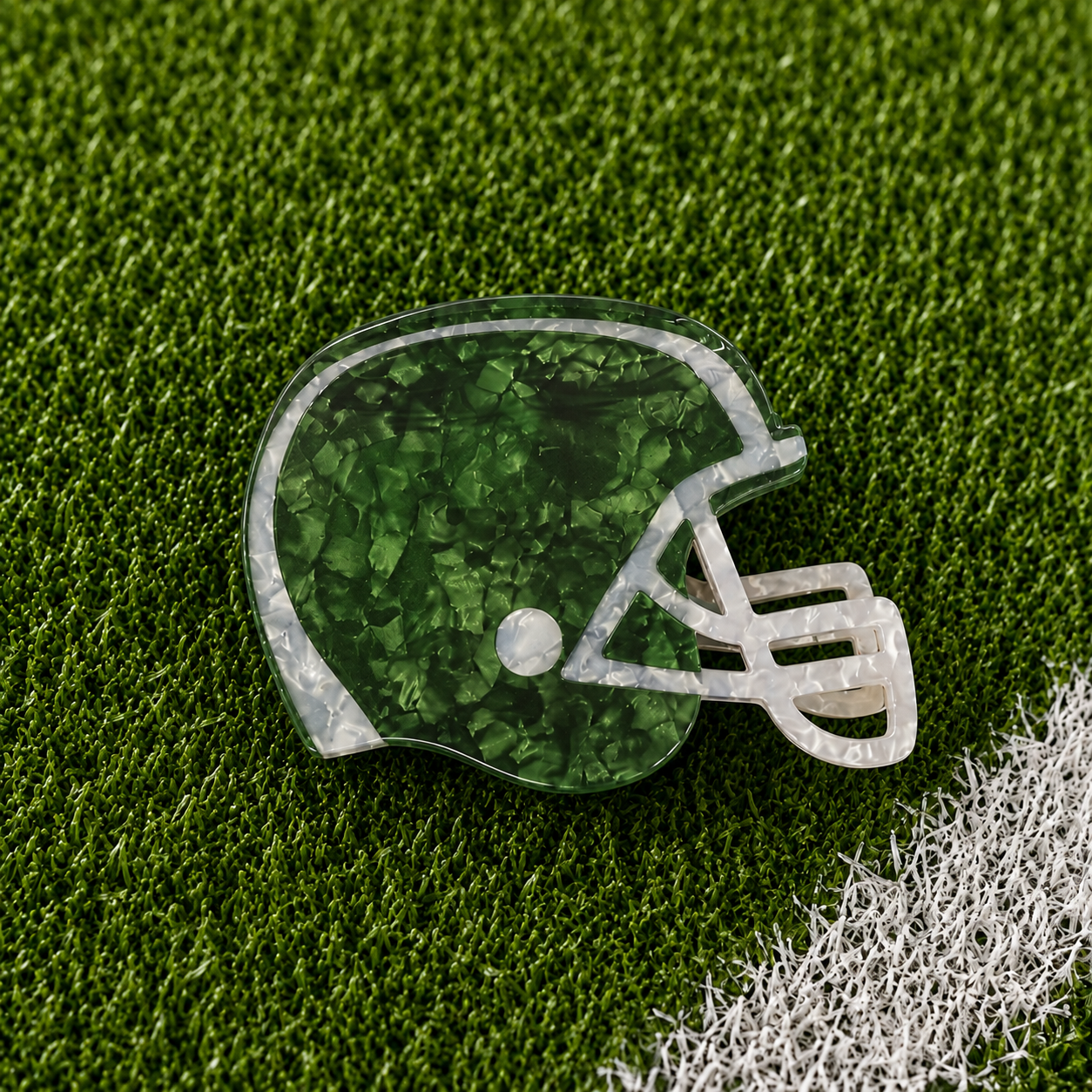 A green football helmet shaped claw clip on green turf background