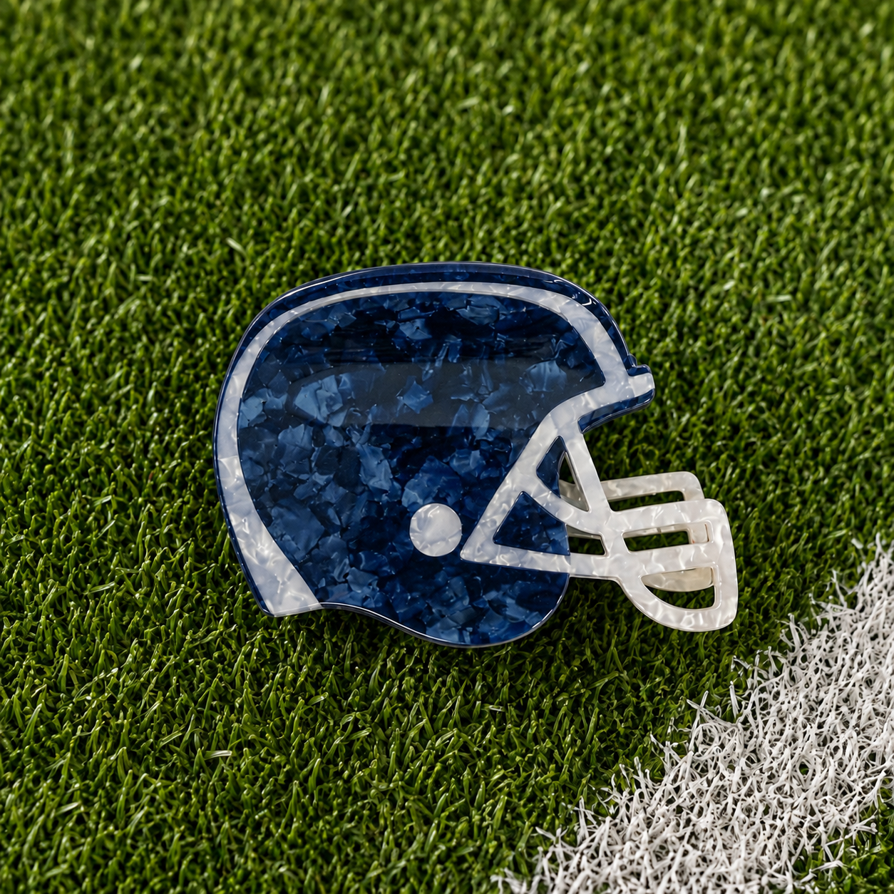 A navy football helmet shaped claw clip on green turf background