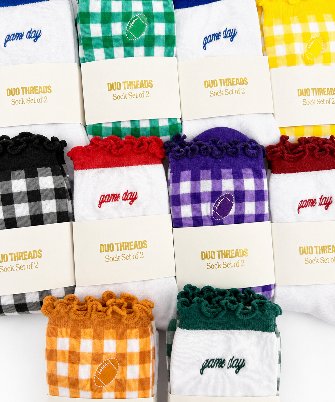 Eight pairs of sock sets arranged in a grid, each with a branded cream paper sleeve reading 'DUO THREADS Sock Set of 2'. The socks feature different colorways including green-and-white gingham, blue-and-white gingham, yellow-and-white gingham, black-and-white gingham, red-and-white gingham, purple-and-white gingham, orange-and-white gingham, and dark green-and-white gingham.