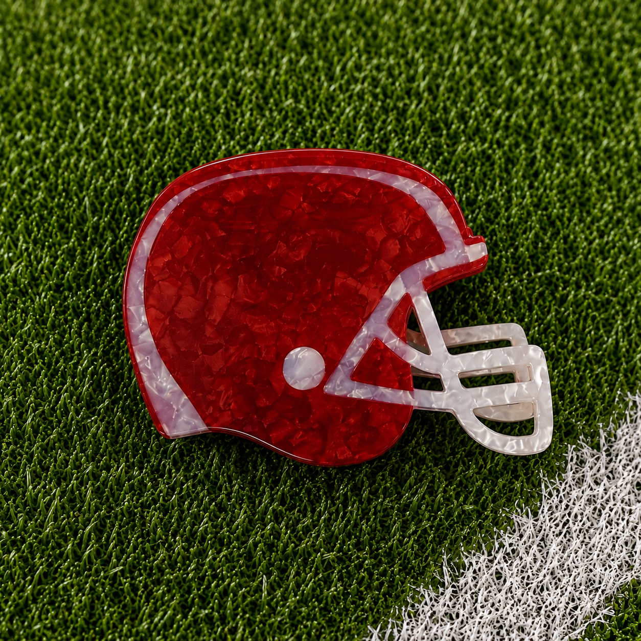 A red football helmet shaped claw clip on green turf background