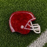 A red football helmet shaped claw clip on green turf background