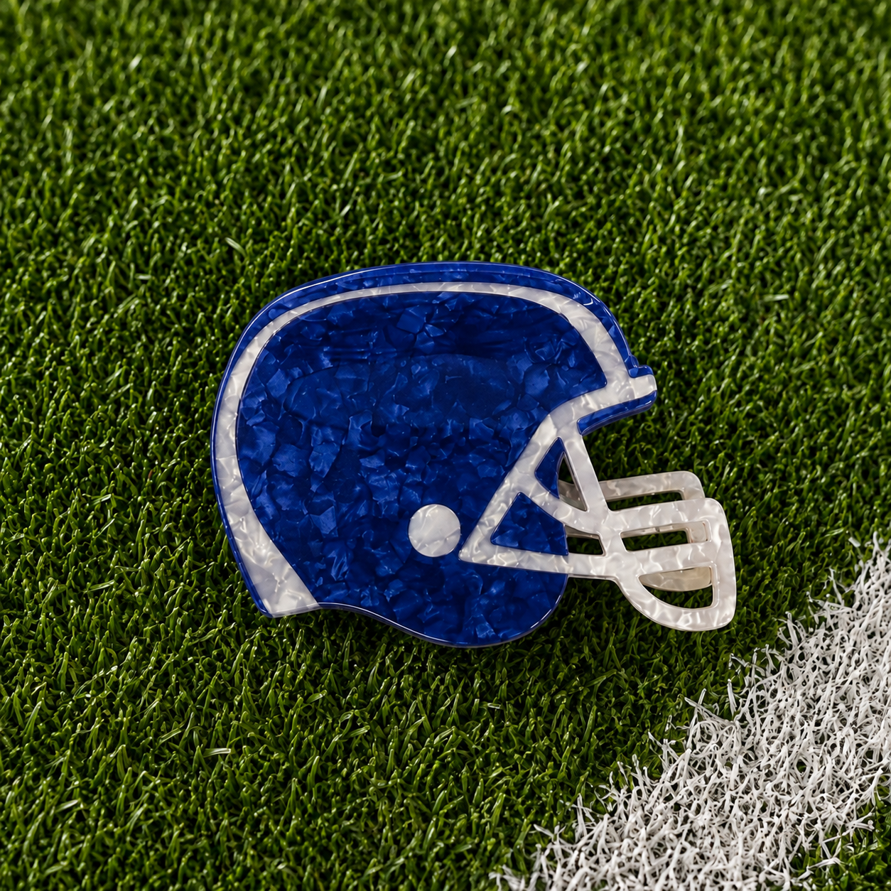 A royal blue football helmet shaped claw clip on green turf background