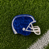 A royal blue football helmet shaped claw clip on green turf background